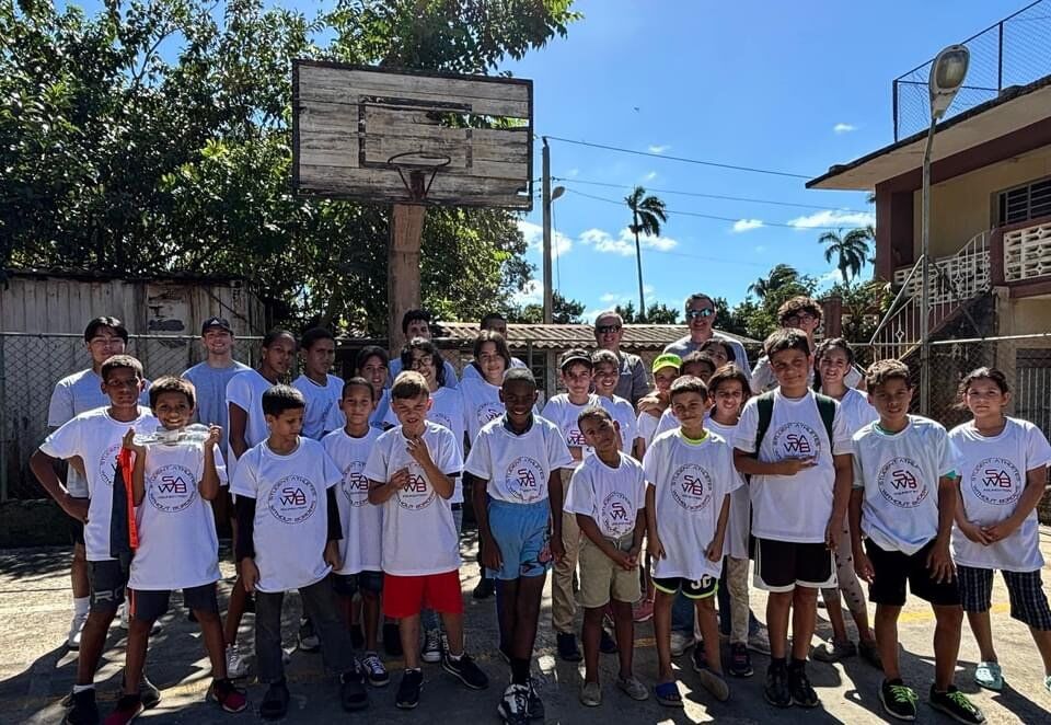 A large group of young players in matching clinic t-shirts standing together on an outdoor court