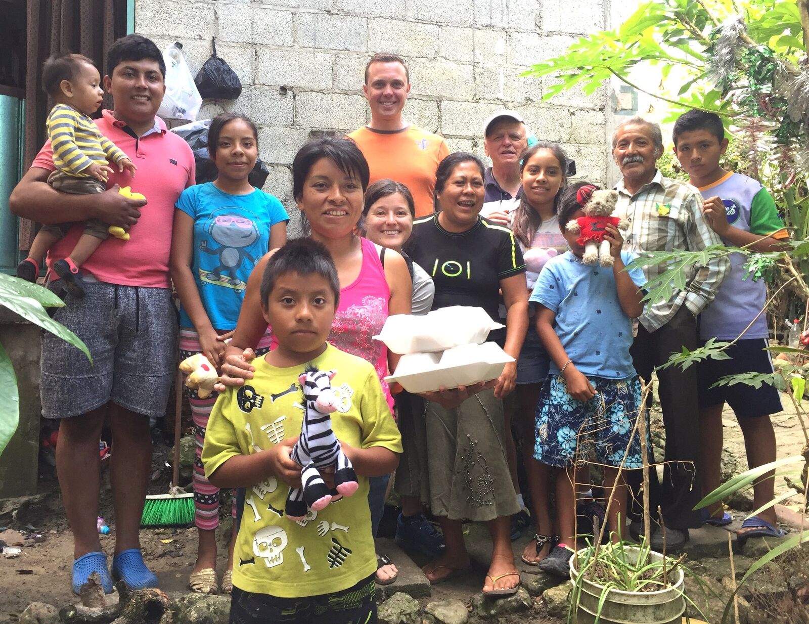 People standing together outside a home, holding bags of donated goods