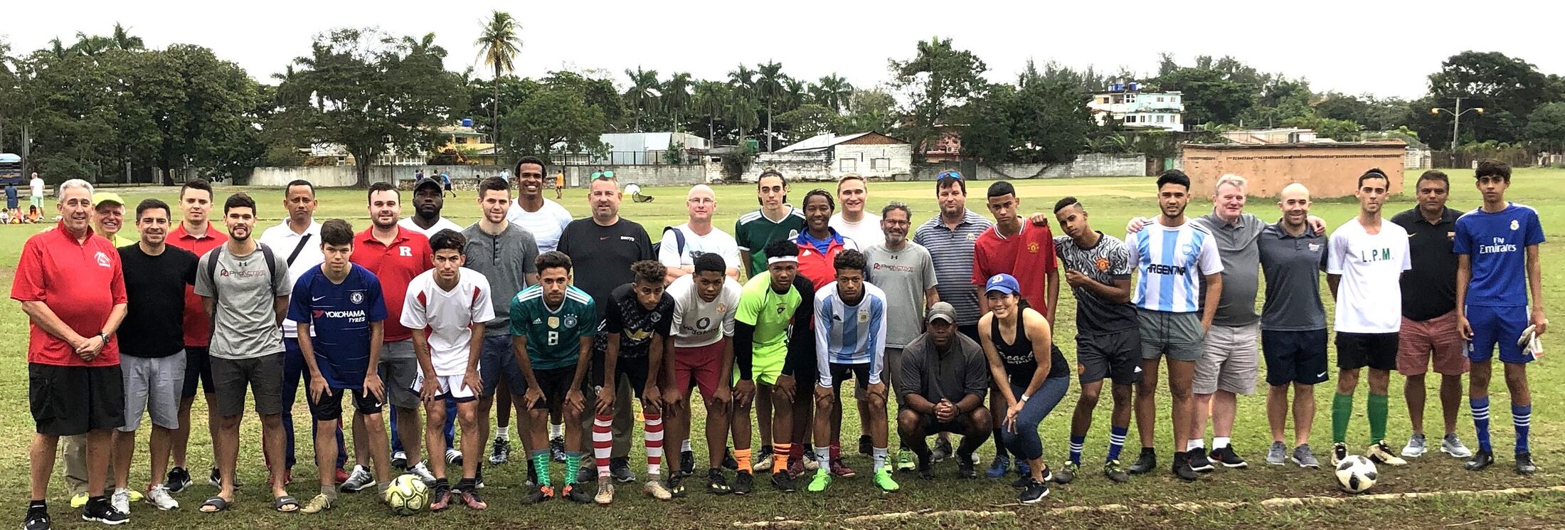 Soccer players and coaches lined up together across a grass pitch