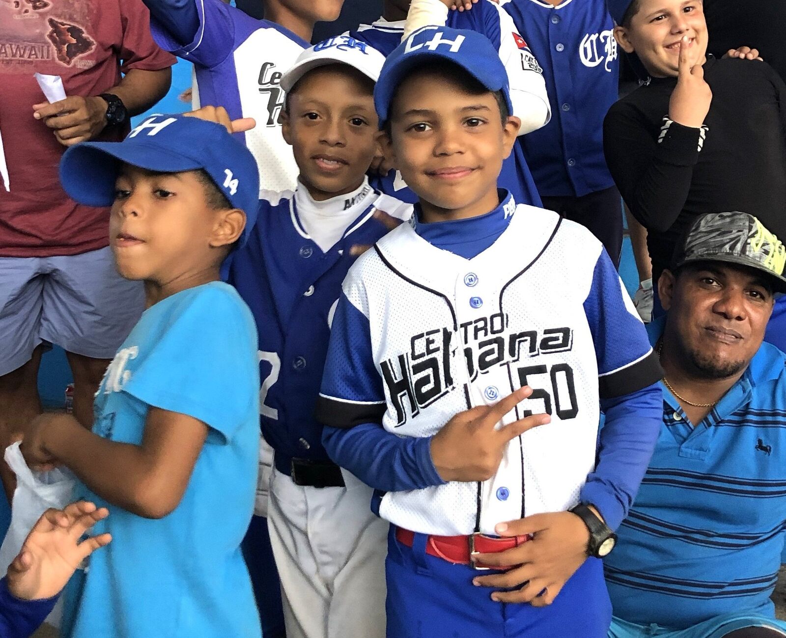 Young baseball players in uniforms and caps smiling together with a coach